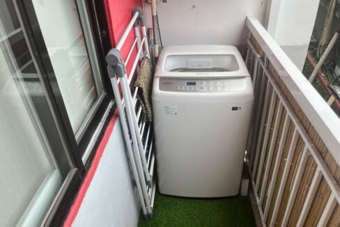 Top-load washing machine on artificial turf on the service balcony
