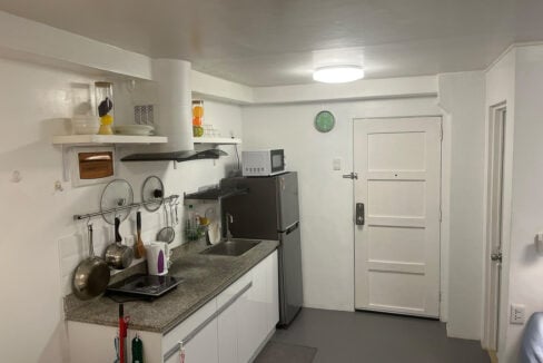 Kitchen counter beside the front door, with open shelves and a microwave