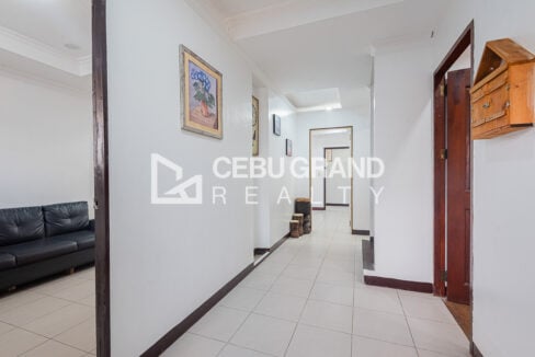 White-tiled hallway with framed artwork leading through the ground floor