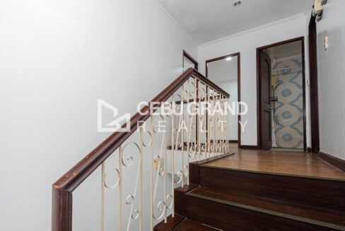 Dark wood staircase with a cream wrought-iron scroll railing