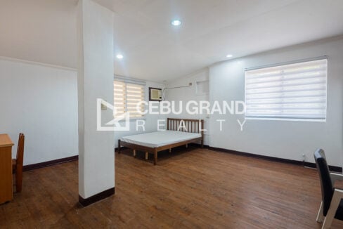 Large upstairs bedroom in the Banilad Town unit with a bed, desk and zebra blinds