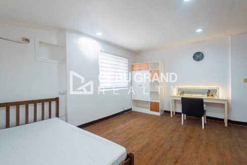 Bedroom with a wooden bed, wardrobe and lit vanity mirror