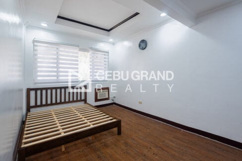 Bedroom at the Banilad townhouse with a wooden bed frame and zebra blinds