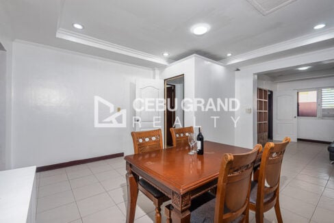 Carved-wood dining table for four under a recessed ceiling