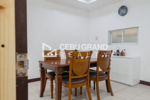 Dining set with carved chairs beside a white sideboard and wall clock
