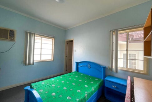 Light blue bedroom with two windows and built-in shelves