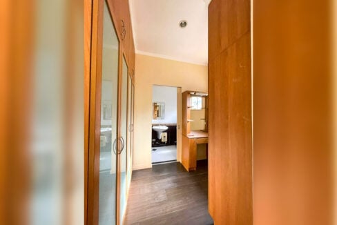 Walk-through closet with mirrored wardrobes and a vanity desk leading to the bathroom