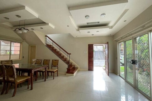 Living and dining area with tray ceilings, a wooden staircase and double front door