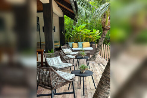 Timber deck with wicker lounge chairs and a sofa under the pavilion roof
