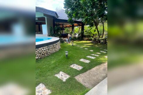 Lawn with stepping stones curving past the pool toward the pavilion and pool bar