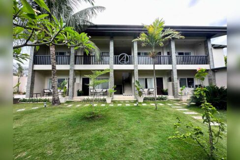 Two-storey guest wing with stone-clad columns, a balcony walkway and patios facing the lawn