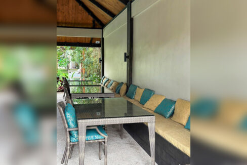 Restaurant seating with glass-topped rattan tables and a long cushioned banquette