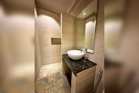 Bathroom with a walk-in rain shower, vessel sink on a granite counter and stone-look tiles