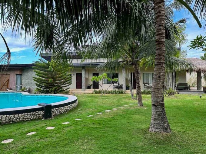 Curved swimming pool on a river-stone base beside the guest rooms and coconut palms