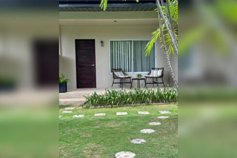 Guest room patio with rattan chairs and a stepping-stone path across the lawn