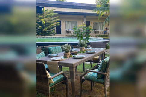 Rattan dining set laid out on the lawn beside the pool