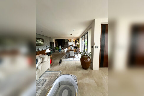 Living and dining hall with a split-stone feature wall and staircase beyond