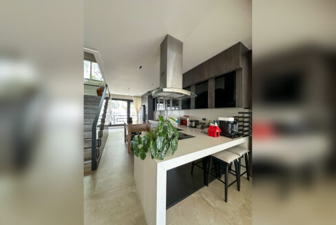 Kitchen with a white waterfall-edge island, induction cooktop and stainless island hood