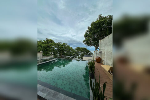 Infinity pool in green mosaic tile with a timber deck and sun lounger