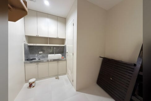 Kitchenette with white cabinets, a vessel sink and a grey stone-look backsplash