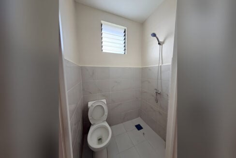 Bathroom with marble-look wall tiles, a toilet, a hand shower and a jalousie window