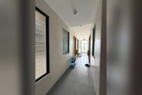 Tiled corridor with jalousie windows and doors to the rental rooms