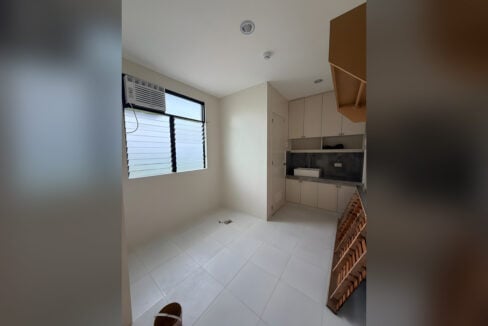 Rental room with white tile floors, a window and a kitchenette at the back