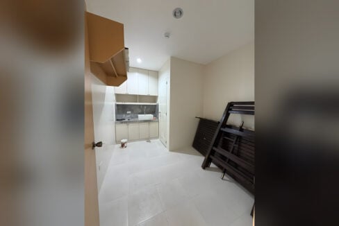 Rental room with a kitchenette and a bed frame, white tile floors throughout