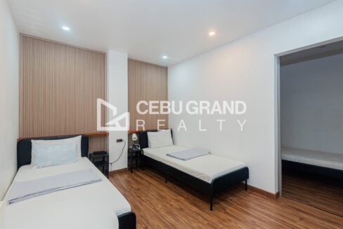 Twin guest room with slatted wood accent wall and wood-look floor