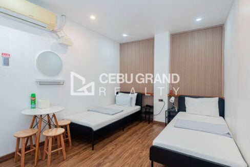 Twin guest room with a round mirror, small table and stools