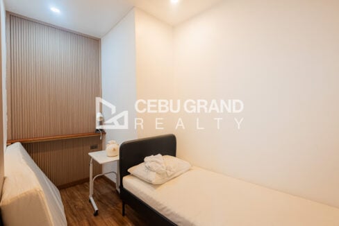 Single bed by a slatted wood panel in a compact guest room