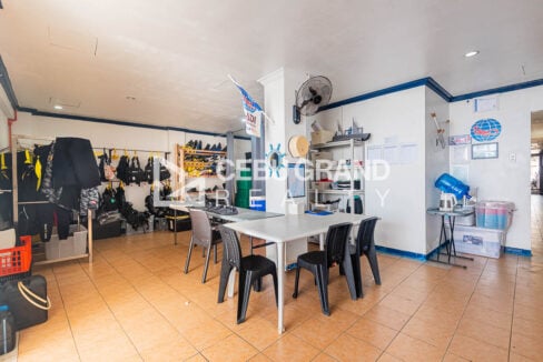 Dive gear room with wetsuits, tanks, worktables and chairs