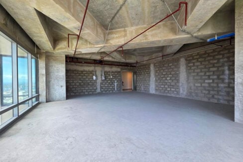 Bare-shell office floor with block walls, electrical panels and the unit entrance