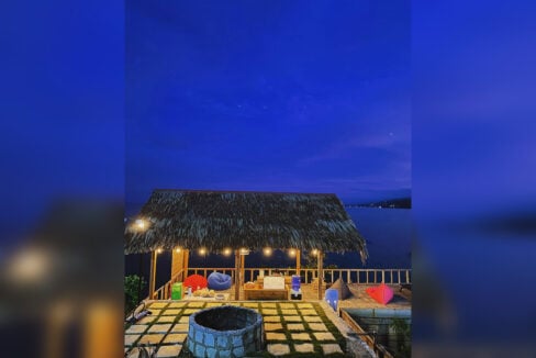 Thatched lounge pavilion with string lights and bean bags at dusk, Dalaguete resort