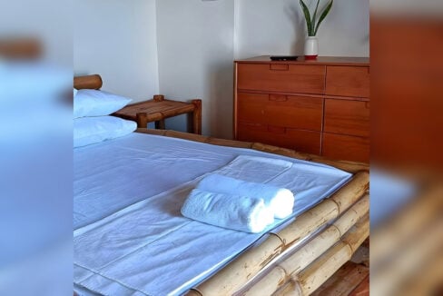 Bamboo bed with rolled towels beside a timber dresser in a Casay resort room