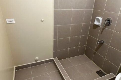 Tiled shower area with curb and mixer