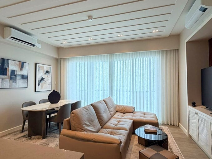 Living area with leather sectional, dining table and grooved feature ceiling at Aruga Resort and Residences, Mactan