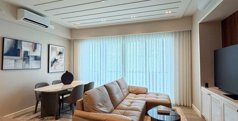 Living area with leather sectional, dining table and grooved feature ceiling at Aruga Resort and Residences, Mactan