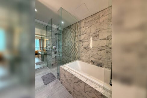 Glass shower and soaking tub with marble walls