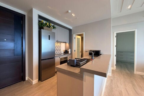 Kitchen with stainless steel refrigerator and quartz breakfast counter in an Aruga condo for sale
