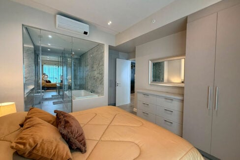 Master bedroom with glass-walled bathroom, dresser and full-height wardrobe