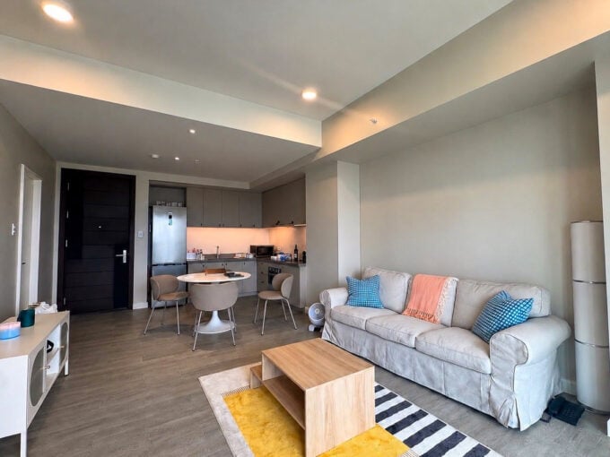 Living area with a slipcovered sofa and timber coffee table, open to the kitchen at Aruga Mactan