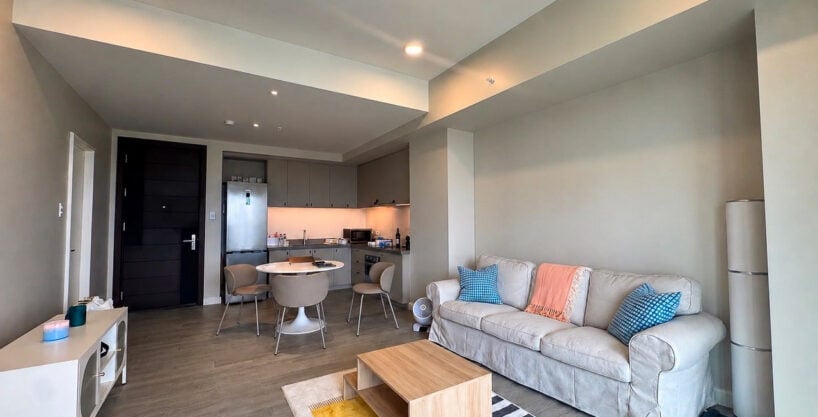 Living area with a slipcovered sofa and timber coffee table, open to the kitchen at Aruga Mactan