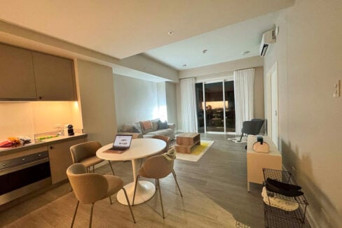 Round white dining table with four chairs, facing the sliding glass doors and living area