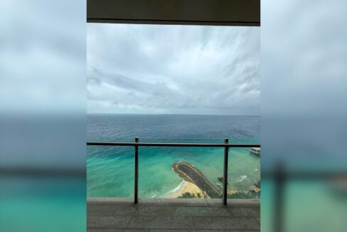 Balcony view over turquoise water, the breakwater and the beach below