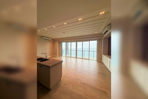 Living and dining area with a kitchen island and sliding doors to the sea-view balcony