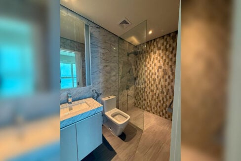 Bathroom with a hexagon mosaic shower wall, marble-look tiles and mirrored cabinet