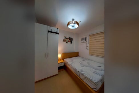 Bedroom with double bed, bedside lamp, white wardrobe and window-type aircon at Avida Tower 2