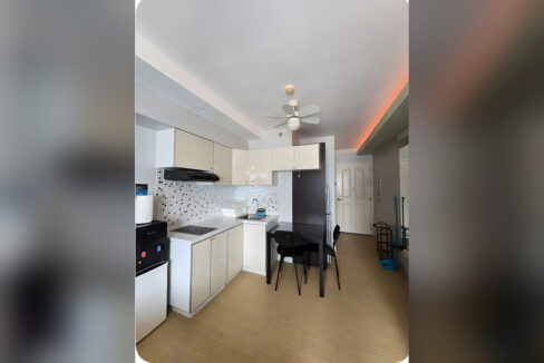 Kitchenette with wood-grain cabinets, mosaic backsplash, induction cooktop and dining table for two