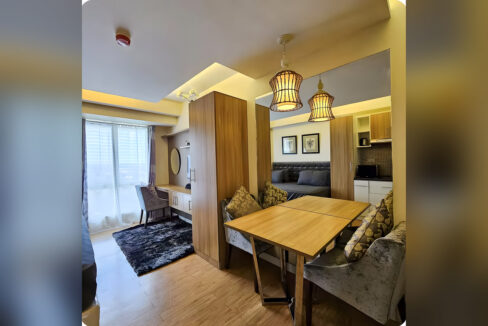 Dining table for four with velvet chairs, desk counter by the window and second bed beyond the wardrobe